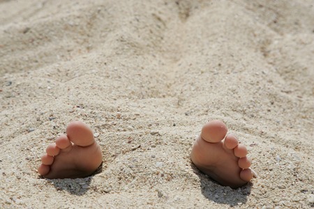 Child's feet in the sand close-up.
