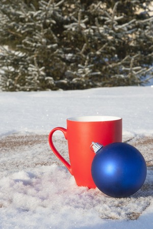 red mug with Christmas balls in the winter forest.の写真素材