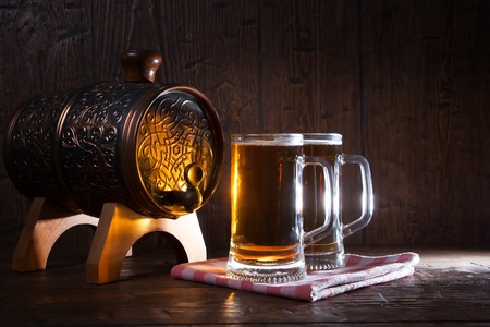 Beer mugs and barrel on a wooden background.の写真素材