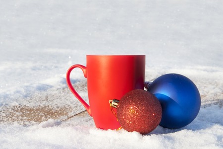 red mug with Christmas balls in the winter forest.の写真素材