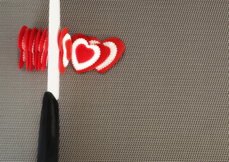 Concept. Ceramic knife cuts red hearts valentines.