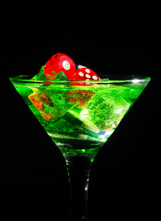 Red dice in a cocktail glass on black background. casino series.の写真素材