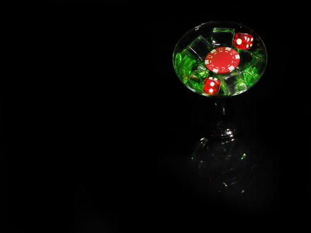 Red dice in a cocktail glass on black background. casino series.の写真素材