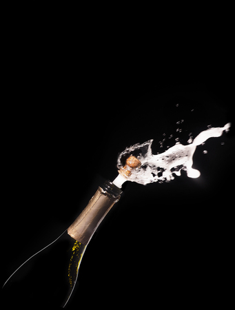 Champagne bottle and spray on black backgroun.の写真素材