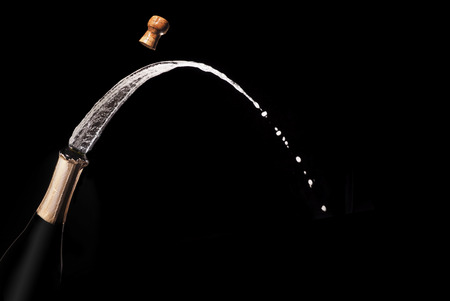Champagne bottle and spray on black backgroun.の写真素材
