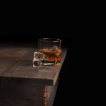 Glass of whiskey on rustic table.black background .