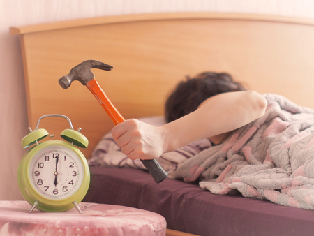 beating the alarm clock with hammer. concept of sleep.の写真素材