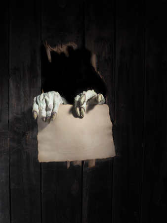 Zombie hand through hole cracked in rustic wood.Halloween theme.の写真素材