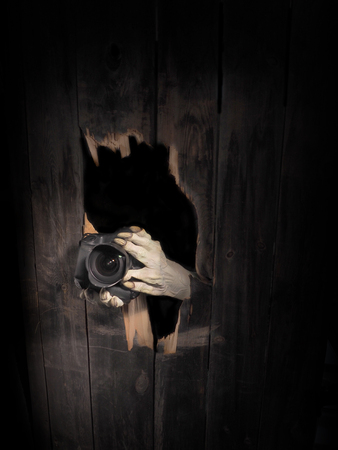 Zombie hand through hole cracked in rustic wood.Halloween theme.