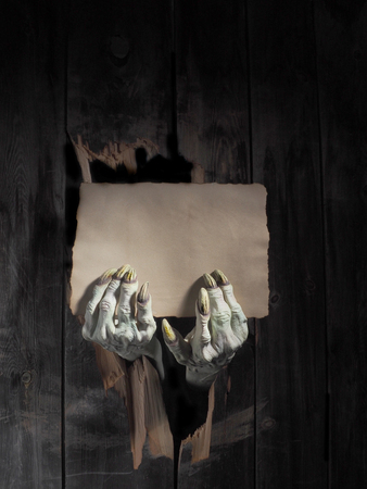 Zombie hand through hole cracked in rustic wood.Halloween theme.の写真素材
