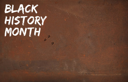 February is Black History Month. Sign on rustic background.