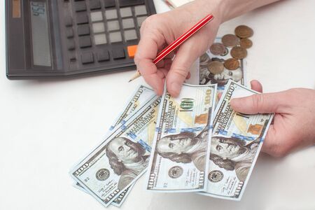 Close-up of hands counting money American dollars. With the help of a calculator. Planning your...