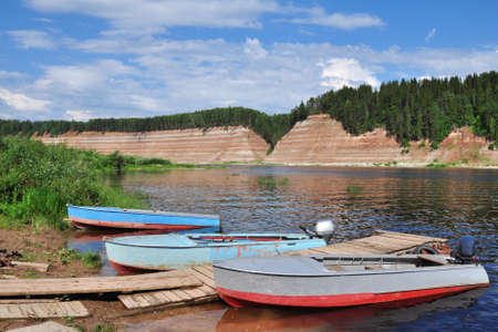three boats are moored on the river Bank.High Bank, rocky, steep. Exposed geological rock, which is...