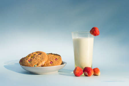A glass of milk, oatmeal cookies on a plate and fresh strawberries. Healthy, delicious, natural,...