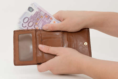 Close-up on white background female hands take out banknotes from brown wallet. Horizontal photo. Concept - payment, waste, purchases.の写真素材