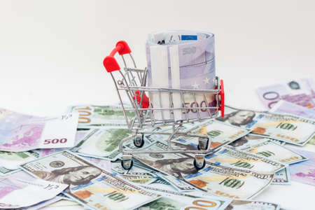 on a large amount of money spread out on the table stands a supermarket trolley filled with euro...