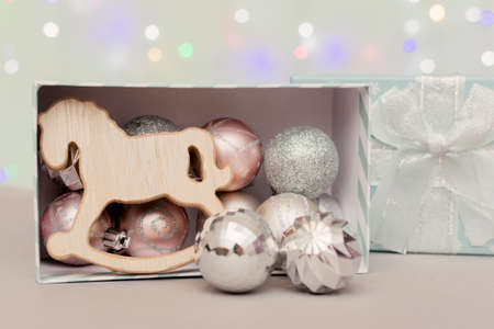 Christmas toys, balls and a horse on the background of bokeh of Christmas lights lie in an open box....