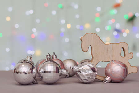 against the background of bokeh of Christmas lights, Christmas balls and a Christmas tree toy - a wooden rocking horse. Concept - New Year card. Soft focusの写真素材