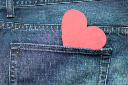 red wooden heart in the back pocket of jeans. Background for text. The idea is to take my heart with...