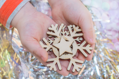 wooden snowflakes - Christmas tree toys lie on childrens palms. Top view, close-up, horizontal...