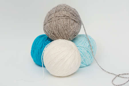 Four balls of yarn for knitting lie in the form of a pyramid on a white background. Gray, white,...