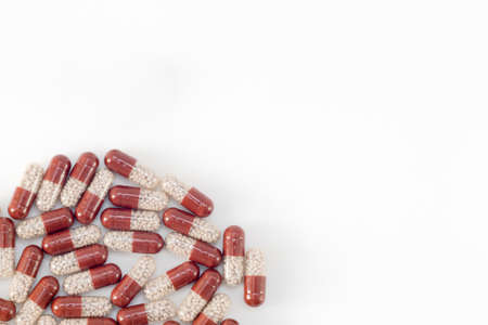 pills are scattered on a white background, brown with white granules inside. View from above. Horizontal photo. Place for your textの写真素材