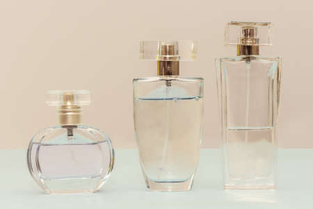 three bottles of toilet water, stand on a beige background. Close-up. horizontal photo. Female perfume, aromaの写真素材