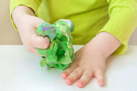Close-up of childrens hands playing with soft plasticine. Concept - restoration of arm muscles after injuries, development of creative thinking, helps to relieve stress, get rid of aggression.の写真素材