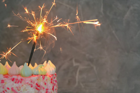close-up on a dark background a cake with a lit sparkler. Concept - holiday, celebration, birthday. Horizontal photo, copy space.の写真素材