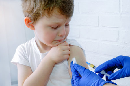 the boy looks frightened at the syringe with which he is injected into his shoulder. A 5 year old...