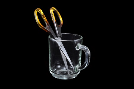 Scissors in a glass mug on a black backgroundの写真素材