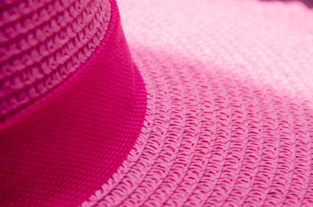 woven hat with a pink ribbon sun in the background.の写真素材