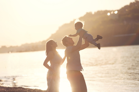Silhouette concept. Happy mother and father playing with little son at sunset. Young caucasian mom and dad with her baby boy having fun outdoor in evening. Happy familyの写真素材