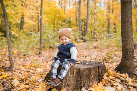 Beautiful baby boy one-year-old crawling, smiles and laughs in fallen leaves - autumn scene. Toddler have fun outdoor in autumn yellow parkの写真素材
