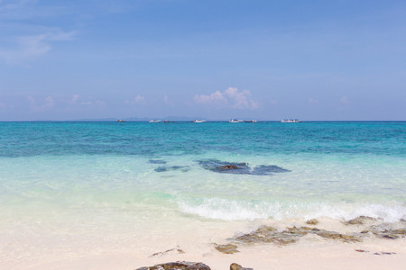 Blue sea and white sand with tropical mountains in the backgroundの写真素材