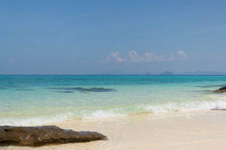 Blue sea and white sand with tropical mountains in the backgroundの写真素材