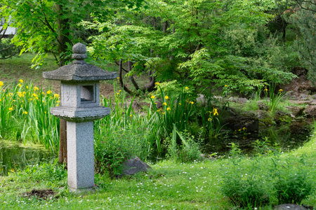 A serene Japanese Garden with a stone lantern, vibrant flora, and natural beauty for relaxationの写真素材