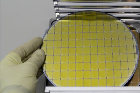 Silicon Wafers in steel holder box on table taken out by hand in gloves- A wafer is a thin slice of...