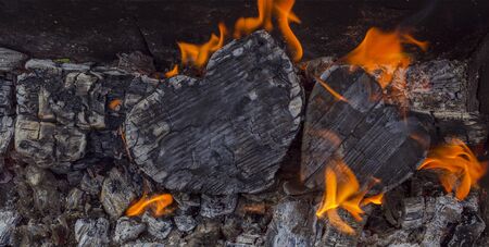 Hot coals and burning woods in the form of human heart. Glowing and flaming charcoal, bright red...