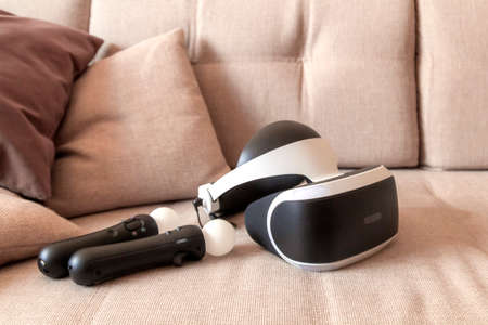 Moscow,Russia - April 12 2020 A playstation 4 VR headset together with a playstation 4 controller and two move controllers on a sofa, ready to start gaming.のeditorial素材