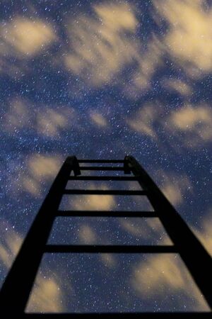 the dark stairs to the night blue starry sky with cloudsの写真素材