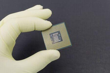 Hand in white glove holding a CPU computer processor microchip.Background is dark grey color.の写真素材
