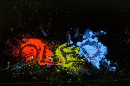 Luminescent organic materials in the form of a powder on black background glow in ultraviolet light.の写真素材
