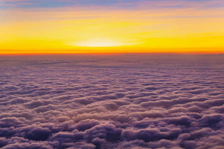 Beautiful and colorful sunset above clouds. Looking through an airplane window.