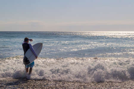 Male surfer entering the sea with his board. Surfer entering the ocean .Ready for a great surfing...