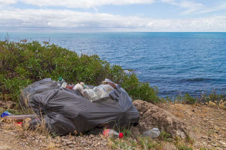 Spilled garbage on the beach of the big city. Empty used dirty plastic bottles. Dirty sea sandy...
