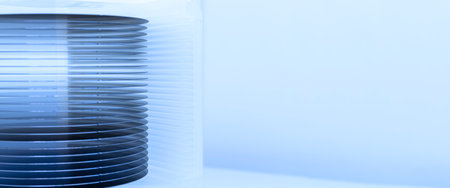 A batch of silicon wafers packed in a plastic storage box in the clean room of a semiconductor foundry ready for microchip production.の写真素材