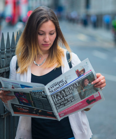Beautiful young woman reads the newspaper in Londonのeditorial素材
