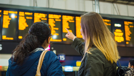 Tourists pointing on a departure time table at a train stationのeditorial素材