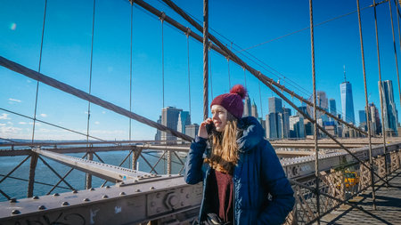 Young beautiful woman relaxes on Brooklyn Bridge while enjoying the amazing view - NEW YORK, UNITED STATES - DECEMBER 4, 2018のeditorial素材